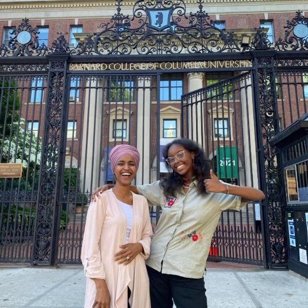 Isra Hirsi and Ilhan Omar standing in front of a gate