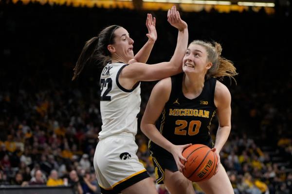 Caitlin Clark (22) defends against Michigan forward Alyssa Crockett (20) during the first half