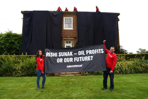 Greenpeace activists pose with a protest poster in front of the manor house of Britain's Prime Minister Rishi Sunak in Yorkshire, England, on Aug. 3, 2023. 