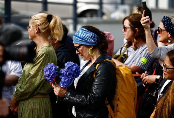 People gather outside late Irish singer Sinead O'Connor's former home on the day of her funeral procession, in Bray, Ireland