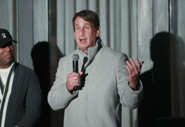 Bryan Freedman in a grey coat holding a microphone at the Pre-Holiday Showcase hosted by Dio<em></em>nne Warwick and Brooke Burke in Malibu, California