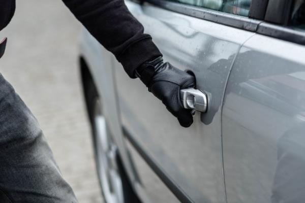 Close up on car thief hand pulling the handle of a car. Car thief, car theft concept