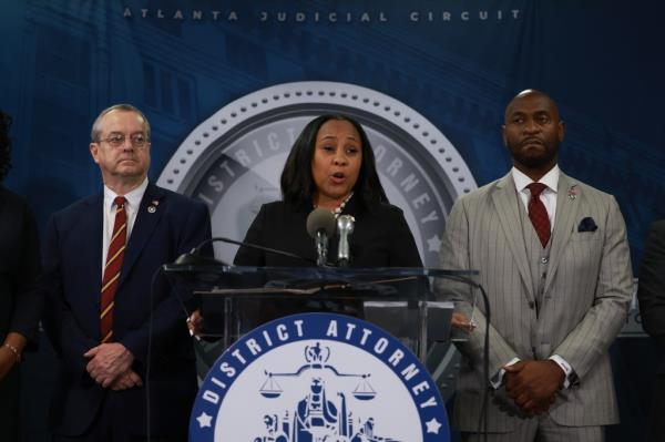 Fani Willis and Nathan Wade stand at a lectern during a press co<em></em>nference  