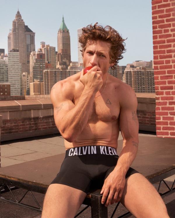 Jeremy Allen White eating an apple while in Calvin Klein underwear with NYC skyline in background