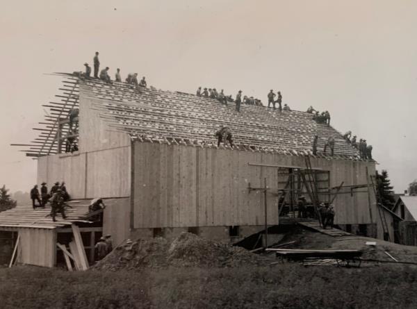 Stutzman family bard being rebuilt by dozens of workers on roof. 