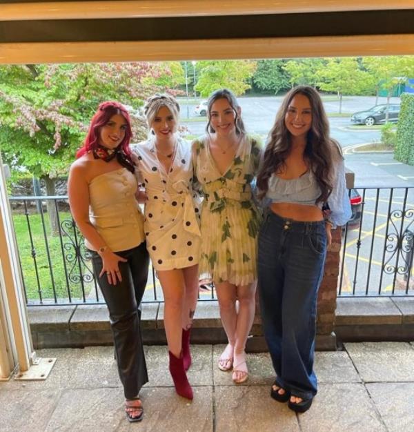 Molly and three other friends posing and looking to camera, all dressed up for a night out