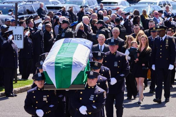 Stephanie Diller holding her son, Ryan, while pallbearers, including Brad Jacobs and Pedro Abrunhosa, carry the casket of slain NYPD Officer Jo<em></em>nathan Diller to a Hearse at his funeral