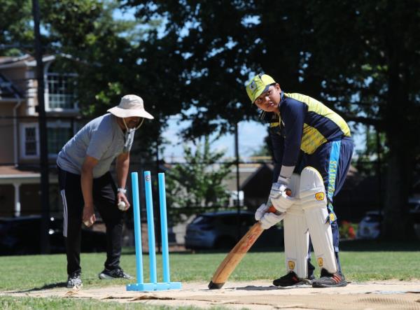 Manvik Goyal, 10, takes his turn at bat while his father Rahul plays wicket keeper.