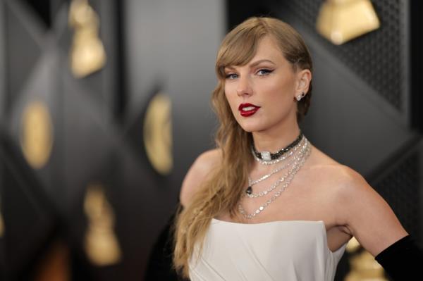 Taylor Swift wearing red lipstick and a white dress at the 66th GRAMMY Awards in Los Angeles, California, February 04, 2024