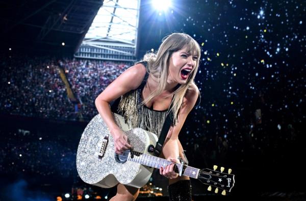 Taylor Swift performing on stage with a guitar during The Eras Tour at Principality Stadium, Cardiff, Wales in June 2024