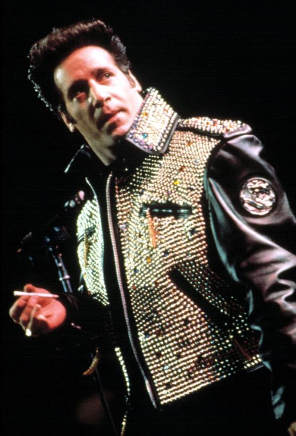 In 1991, Andrew Dice Clay holds a cigarette on stage.