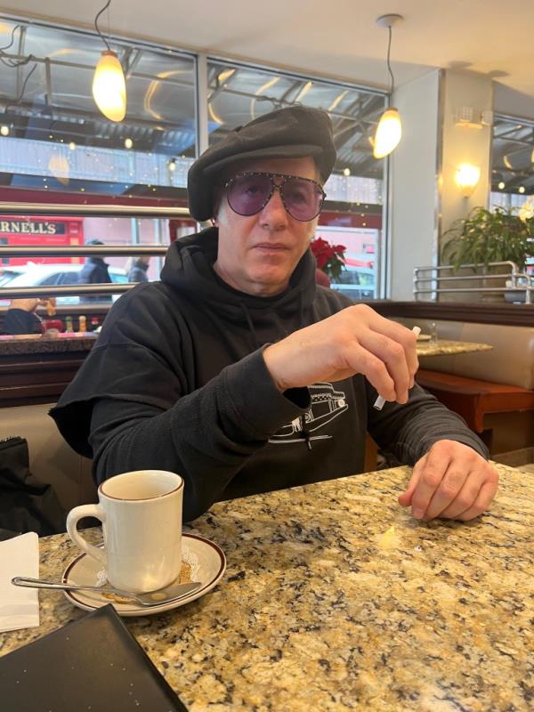 Andrew Dice Clay sitting at a diner table. 