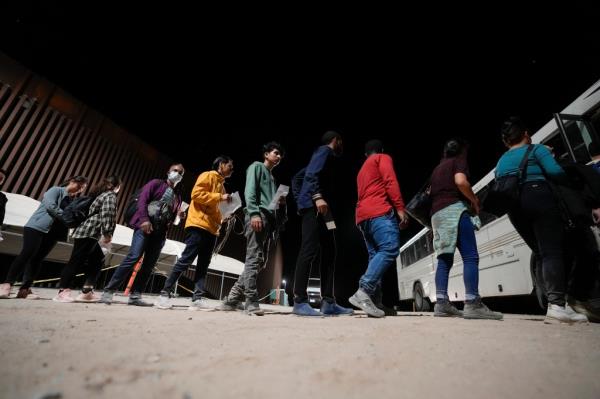 People board a bus as they wait to apply for asylum after crossing the border from Mexico on July, 11, 2023, near Yuma, Arizona. 