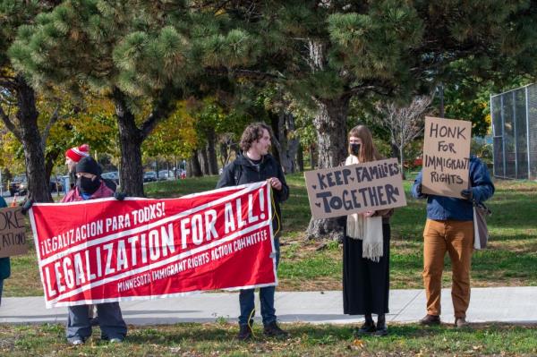 A group of people at a rally in Minneapolis, Minnesota, holding signs in protest against the extension of Trump's border wall