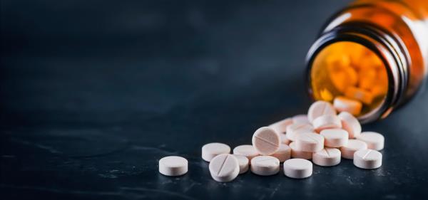 Close-up view of white medical pills and a bottle on a black background