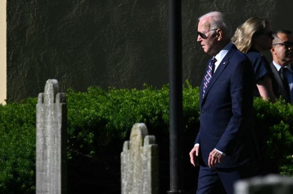 US President Joe Biden, in a suit and tie, walking outside of Saint Joseph on the Brandywine Roman Catholic Church in Wilmington, Delaware, near the cemetery wher<em></em>e his son Beau is buried.