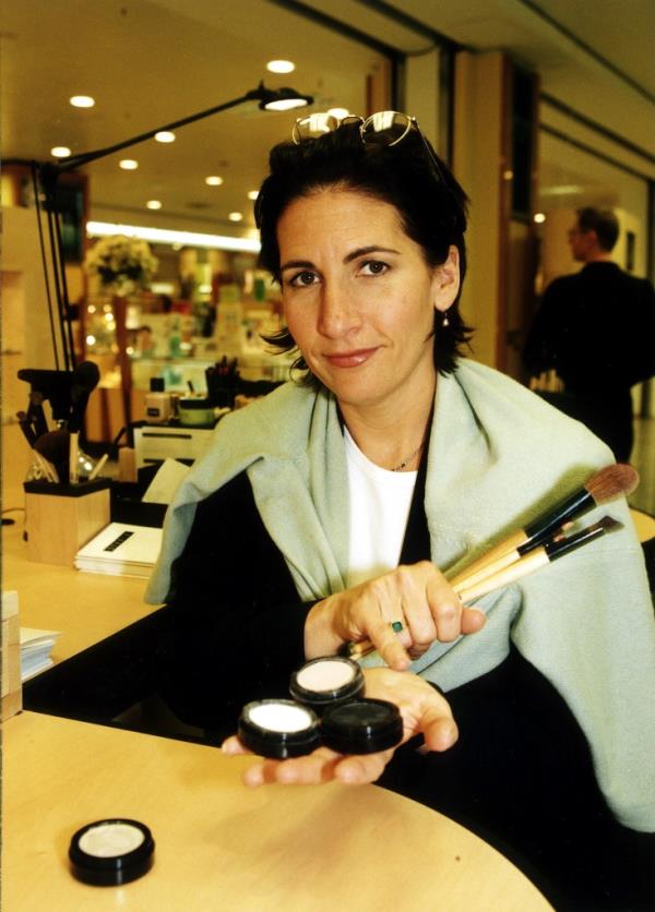 Bobbi Brown sitting at a counter with makeup. 