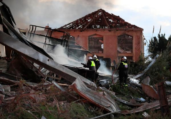 Firefighters extinguish fire at a destroyed warehouse, attacked by Israeli strikes, at an industrial district, in the southern coastal town of Ghazieh.