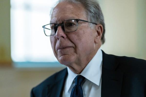 Wayne LaPierre, former CEO of the Natio<em></em>nal Rifle Association, walking in a courthouse hallway in New York, dressed in a suit and tie.