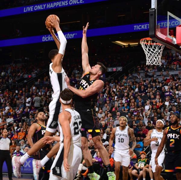 Victor Wembanyama dunks the ball while Drew Eubanks goes for the block in a game against the Phoenix Suns.