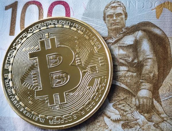 Souvenir bitcoin token next to a 100 ruble bill in Moscow.