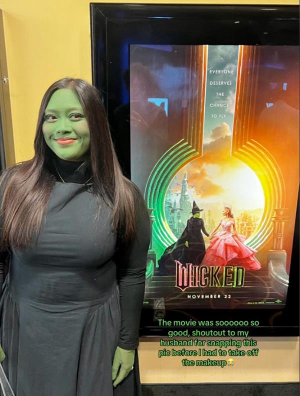 A devoted Wicked fan with her face painted green in front of an AMC theater