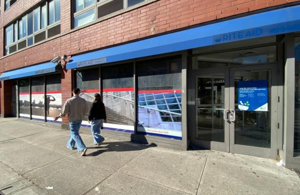 A couple walking past the closed Rite Aide store at 195 8th Avenue in Manhattan, NY with signage indicating closure since December 14, 2022