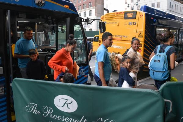 Adults and children getting off a bus in NYS arriving at the Roosevelt Hotel 