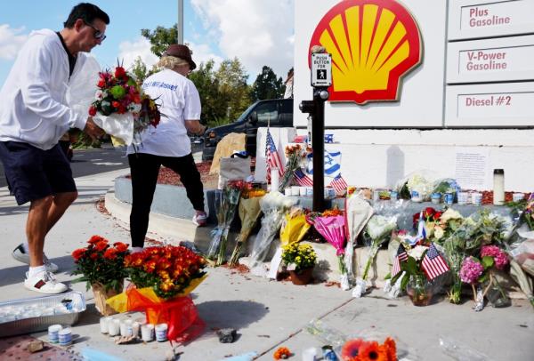 A person places flowers at a makeshift memorial at the site of an altercation 