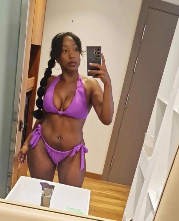 Woman taking mirror selfie in purple bikini.