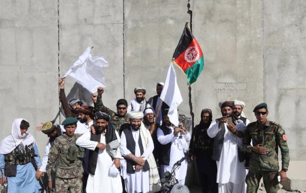 Afghan civilians carrying Afghan natio<em></em>nal flag along with Taliban flag stand with Taliban fighters and army soldiers to celebrate a three-day ceasefire on second day of Eid al-Fitr, in the outskirt of Kabul, Afghanistan, 16 June 2018.  