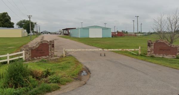 Picture of a barn, fence, a road, and grass.