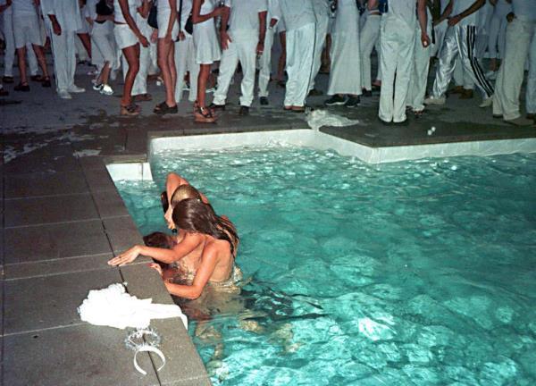 A photo of two women pouring champagne down a third woman's throat in Combs' pool during his 1998 Labor Day party.