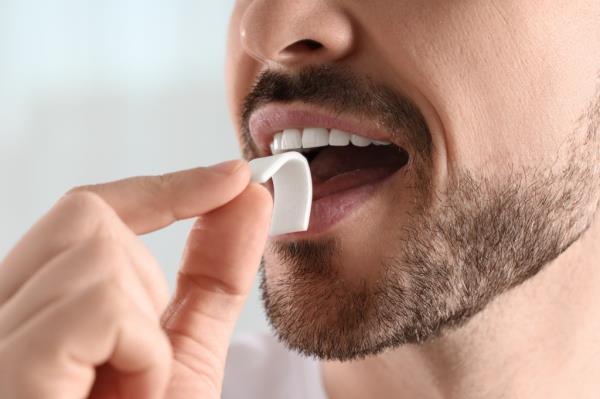 Man putting a piece of specialty gum into his mouth,