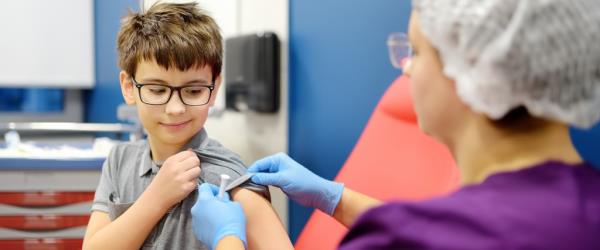 A boy is being vaccinated. A child is given a vaccine during an epidemic or outbreak of a disease. A kid during routine vaccination