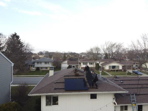 Jared Salvatore, right, and Garrison Riegel of Celestar Solar carry a solar panel o<em></em>nto a roof in Schaumburg on Nov. 30, 2023.