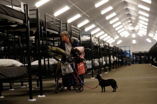 Verna Vasbinder prepares her her new bunk in the city's new Temporary Bridge Shelter for the homeless as her dog, Lucy Lui, looks on Friday, Dec. 1, 2017, in San Diego. The first of three shelters opened Friday, which will eventually provide beds for up to 700 people, as the city struggles to co<em></em>ntrol a homeless crisis gripping the region.