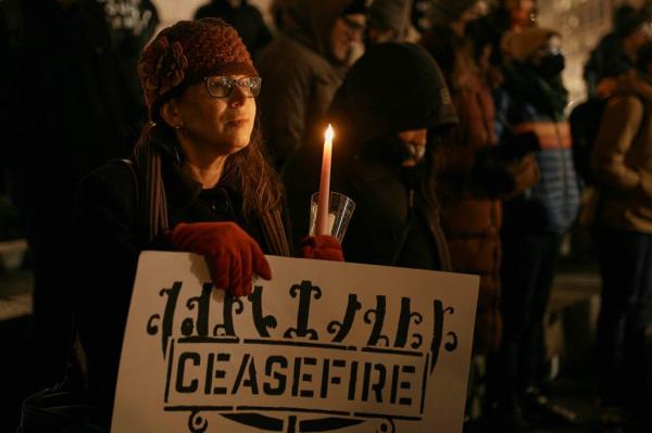 A Jewish woman holds a placard and a candle as Jewish rabbis and members of the community gather demanding a permanent ceasefire in Gaza during the first night of the Jewish holiday of Hanukkah on Thursday, Dec. 7, 2023, in New York. (AP Photo/Andres Kudacki)