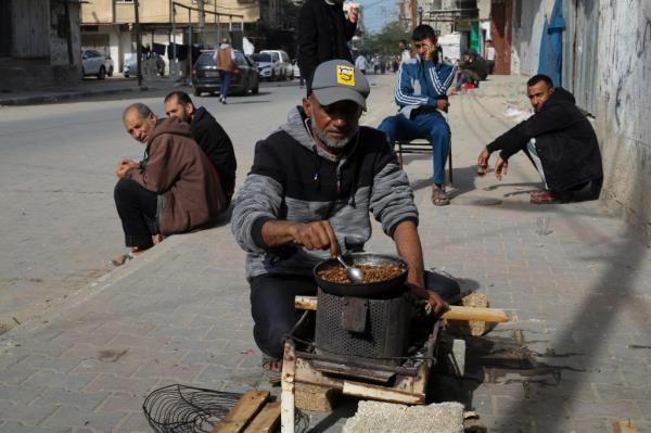 A Palestinian cooks on a sidewalk during the o<em></em>ngoing Israeli bombardment of the Gaza Strip in Rafah on Sunday, Dec. 10, 2023. (AP Photo/Hatem Ali)