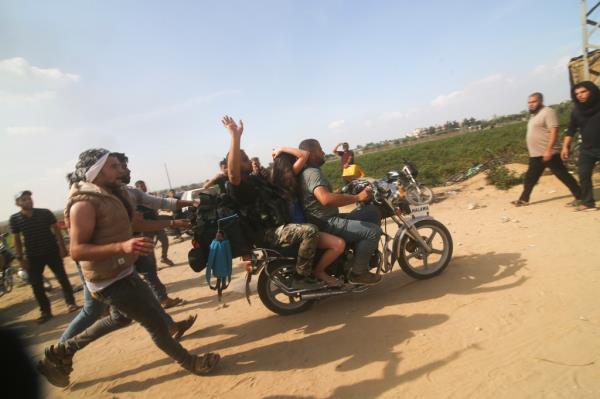 Hamas terrorists transport a captured Israeli civilian on a motorcycle from Kfar Azza kibbutz to the Gaza Strip on Oct. 7, 2023.