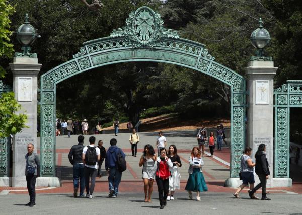 A group of people walking under a green arch on the University of California at Berkeley campus in Berkeley, Calif.